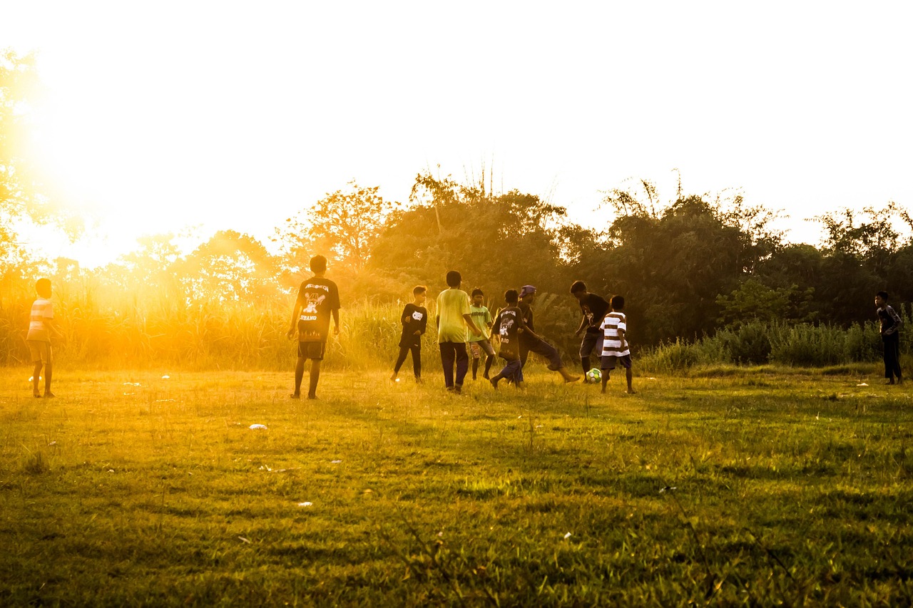 Kids playing football on a field in late afternoon light