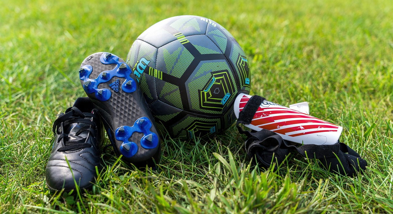 Soccer ball and cleats laid out on grass